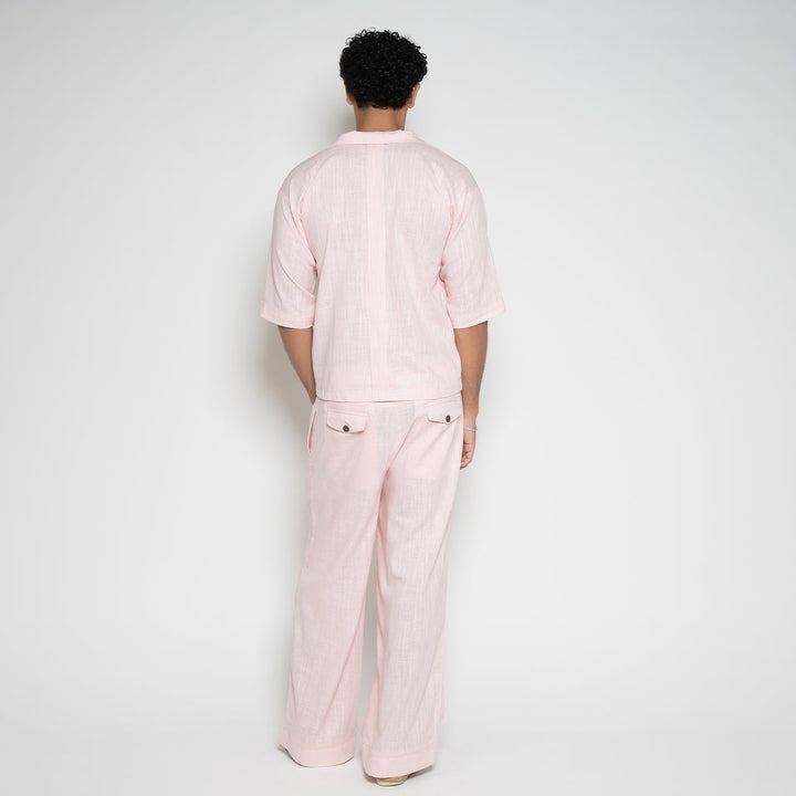 Back view of model highlighting the relaxed fit drape of the Men's Pink Ombre Linen Pants by Flashmob Nation.
